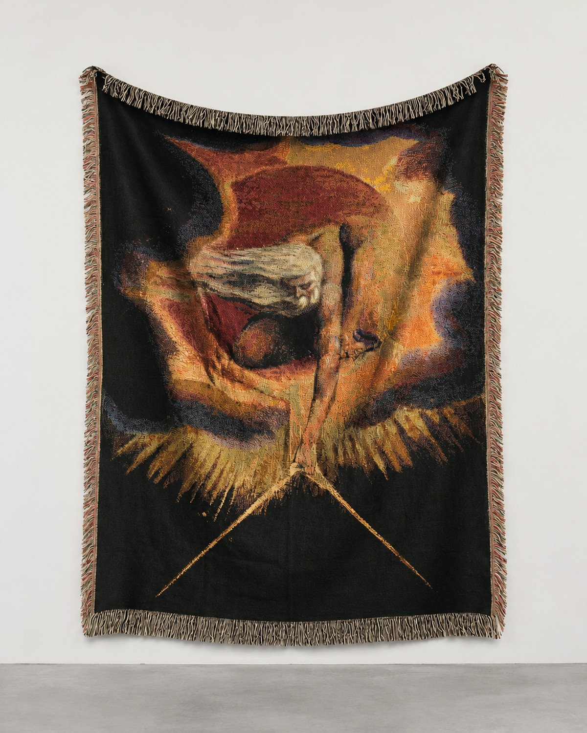 The Ancient of Days woven blanket hung on a white gallery wall: a white-haired figure leaning from a red and gold disc with dividers.