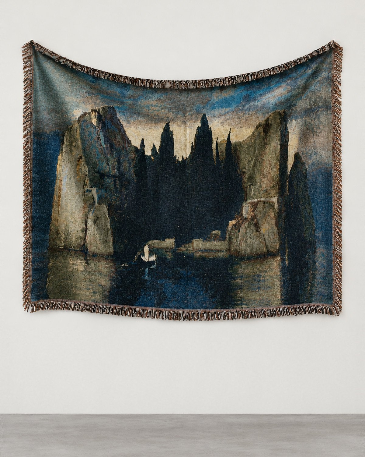 Isle of the Dead woven blanket hung on a white gallery wall: a rocky island of cypresses and a small boat with a figure in white.